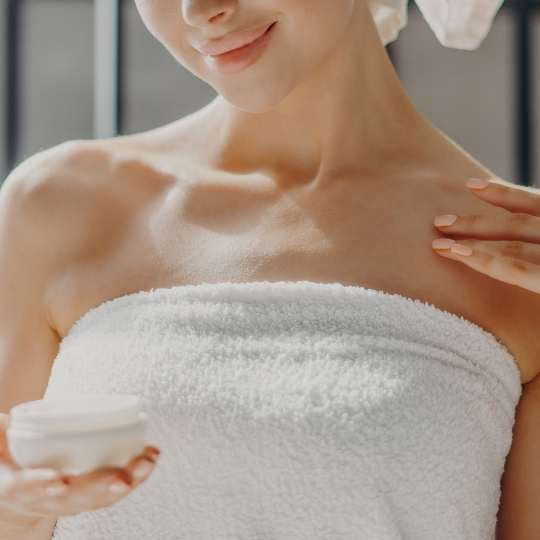 Woman applying moisturizer after shower