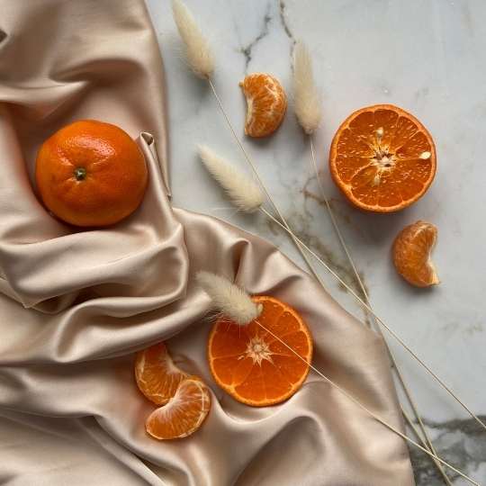 Fresh oranges on silky beige fabric