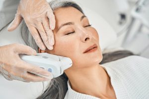 Pleased Asian patient enjoying the procedure of smoothing skin
