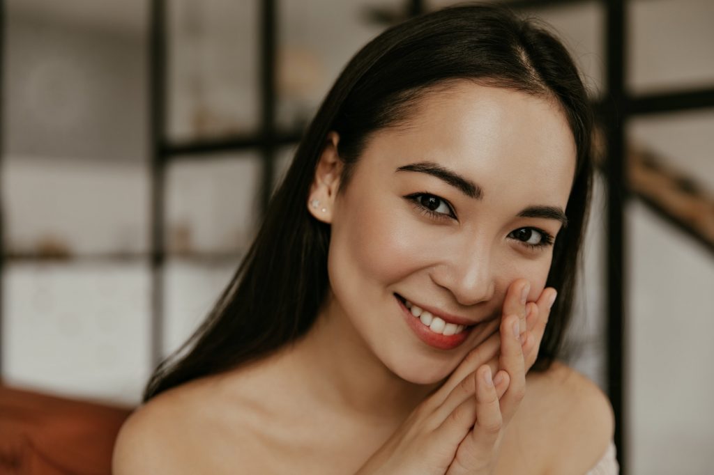 Healthy beautiful woman smiles sincerely. Portrait of brunette attractive Asian lady with good skin