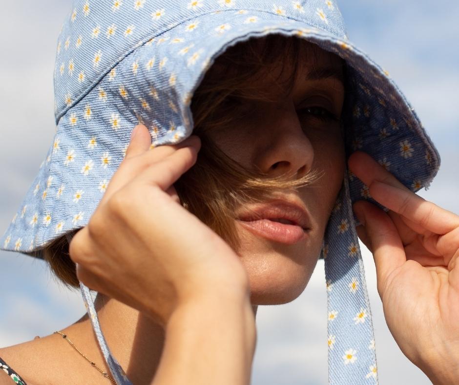 A woman shielding her face from the sun with a hat
