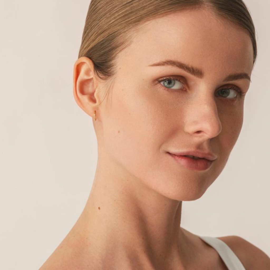 Smiling woman with short hair and earrings.